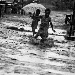 A young boy fall into one of the enormous puddles full of mud of the lane while he was chased by other kids
